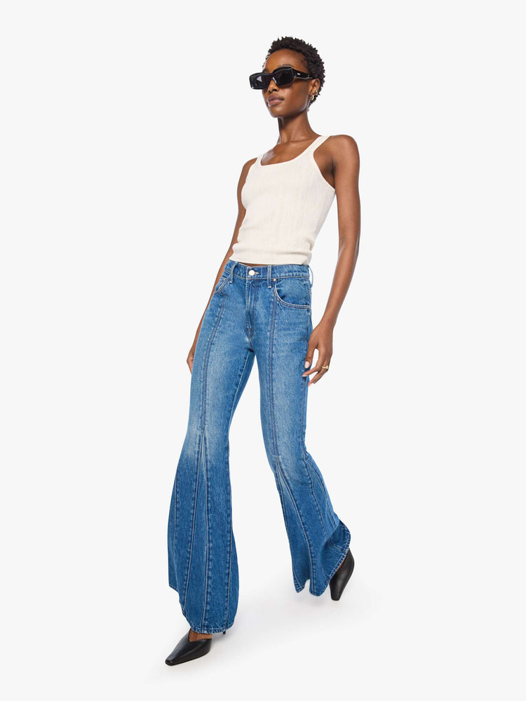 Walking view of a woman in a high-rise jeans have a zip fly, flared leg, seamed details down the front and back, a long 34-inch inseam and a clean hem. 