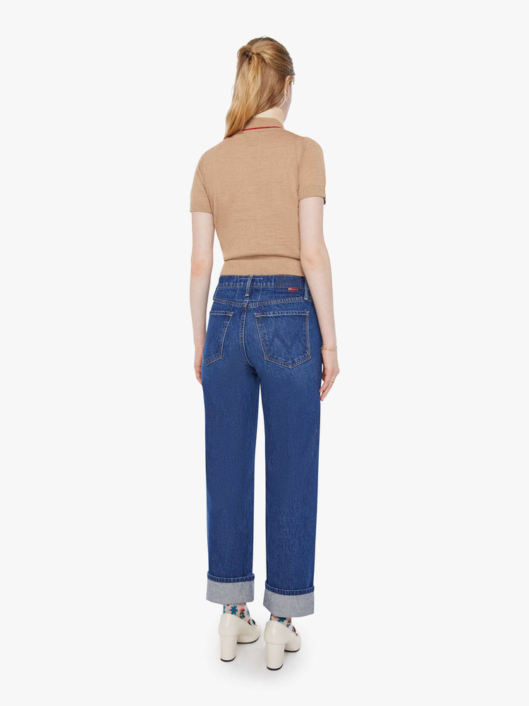 Back view of a woman in a mid blue straight-leg jeans with a high rise, zip fly and 29-inch inseam with a cuffed hem.