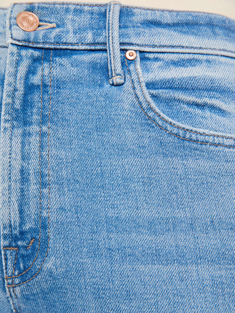 Swatch view of a woman in a light blue with whiskering, fading at the knees and chambray fringe along the outer leg  high-waisted bootcut jean with a zip fly, 32-inch inseam and a clean hem.