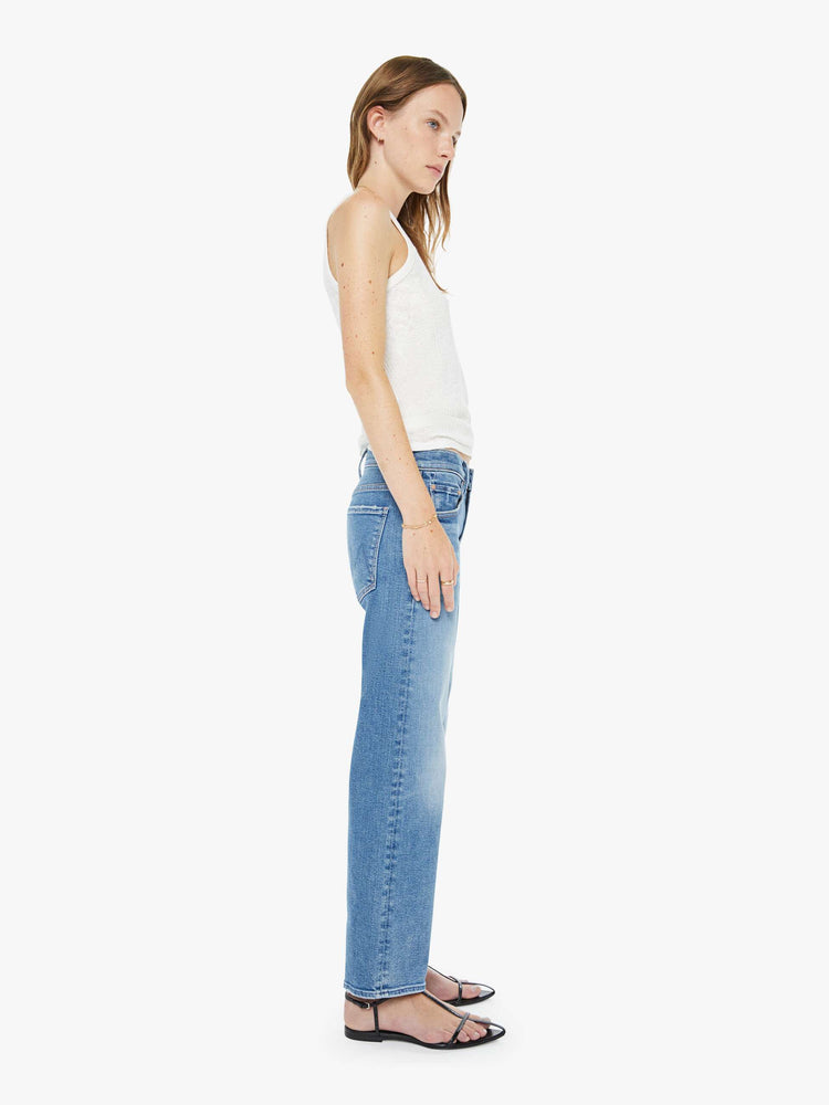 Side view of a woman in a light blue high-rise straight-leg jeans with a zip fly, ankle-length inseam and a clean hem.