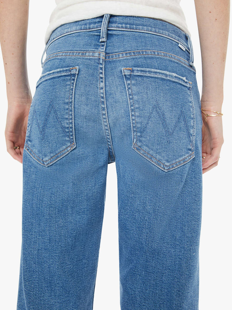 Back close up view of a woman in a light blue high-rise straight-leg jeans with a zip fly, ankle-length inseam and a clean hem.