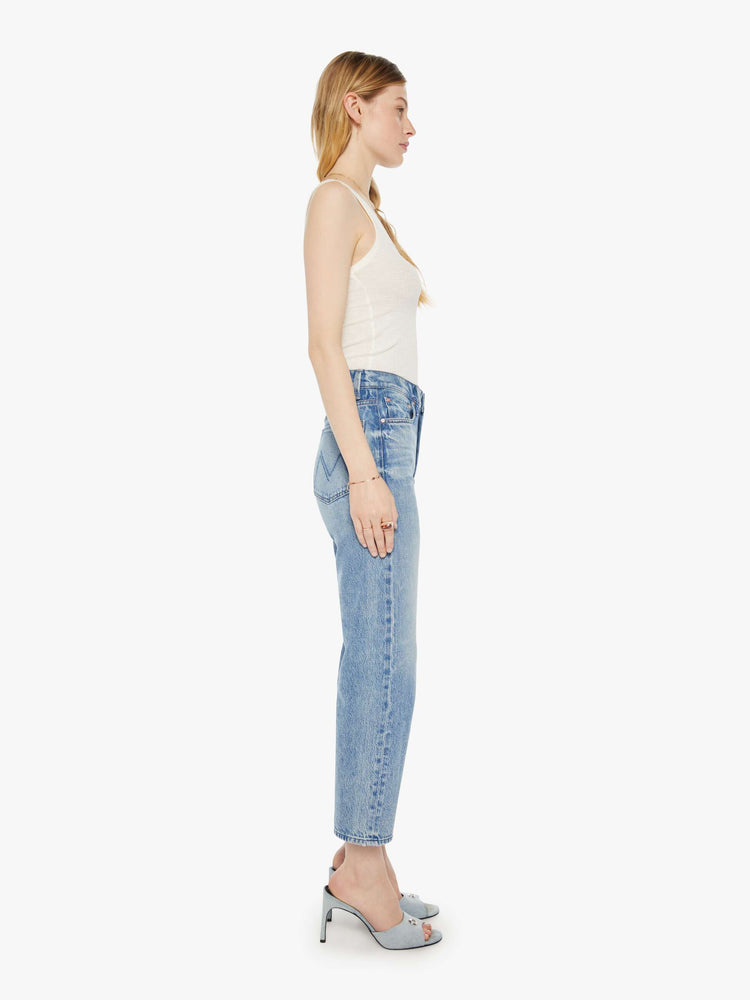 Side view of a woman in a light blue high-rise jeans with a straight leg, zip fly and an ankle-length inseam with a clean hem.