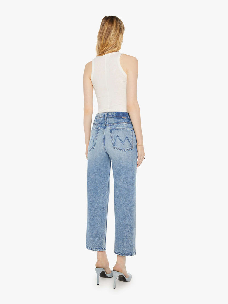 Back view of a woman in a light blue high-rise jeans with a straight leg, zip fly and an ankle-length inseam with a clean hem.