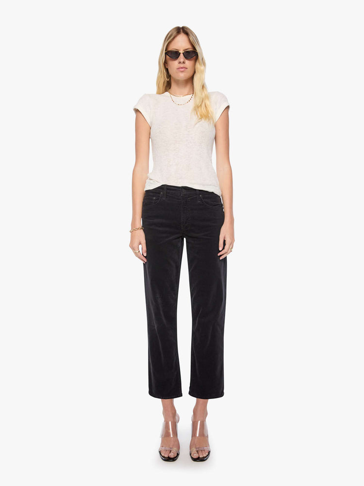 Front view of a woman in a black corduroy mid-rise straight-leg pants with a zip fly, ankle-length inseam and a clean hem.