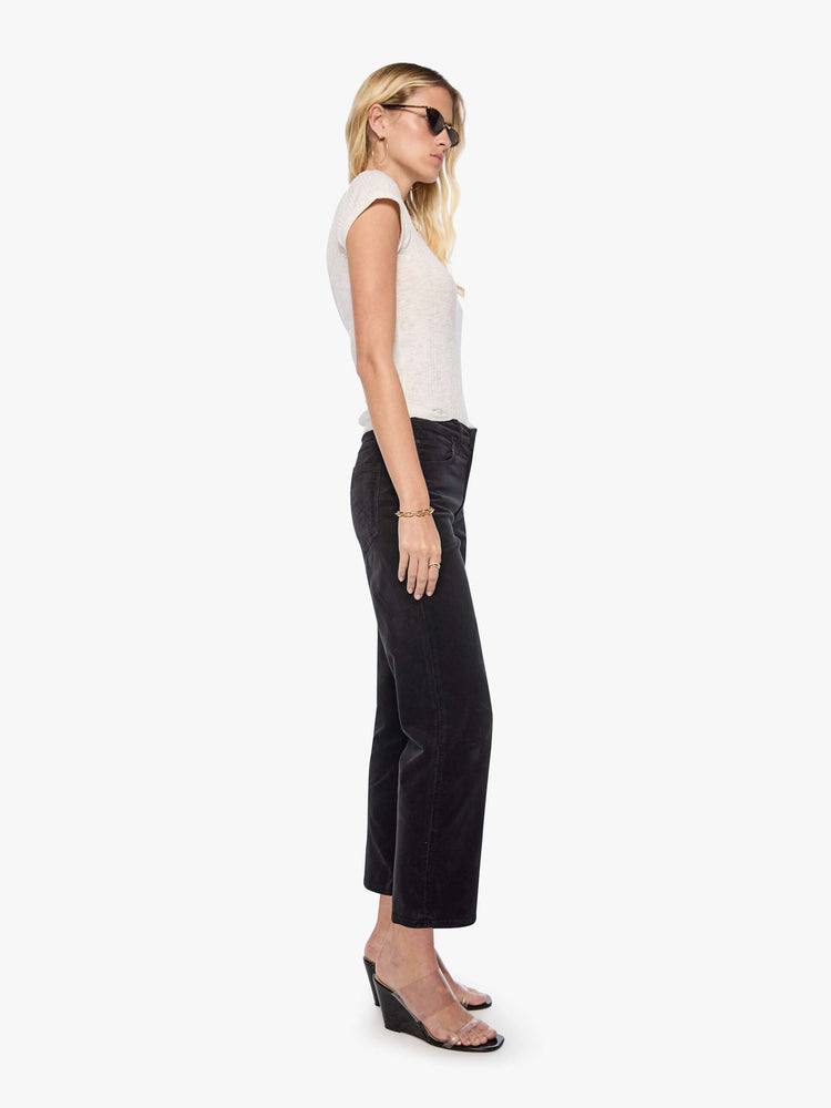 Side view of a woman in a black corduroy mid-rise straight-leg pants with a zip fly, ankle-length inseam and a clean hem.