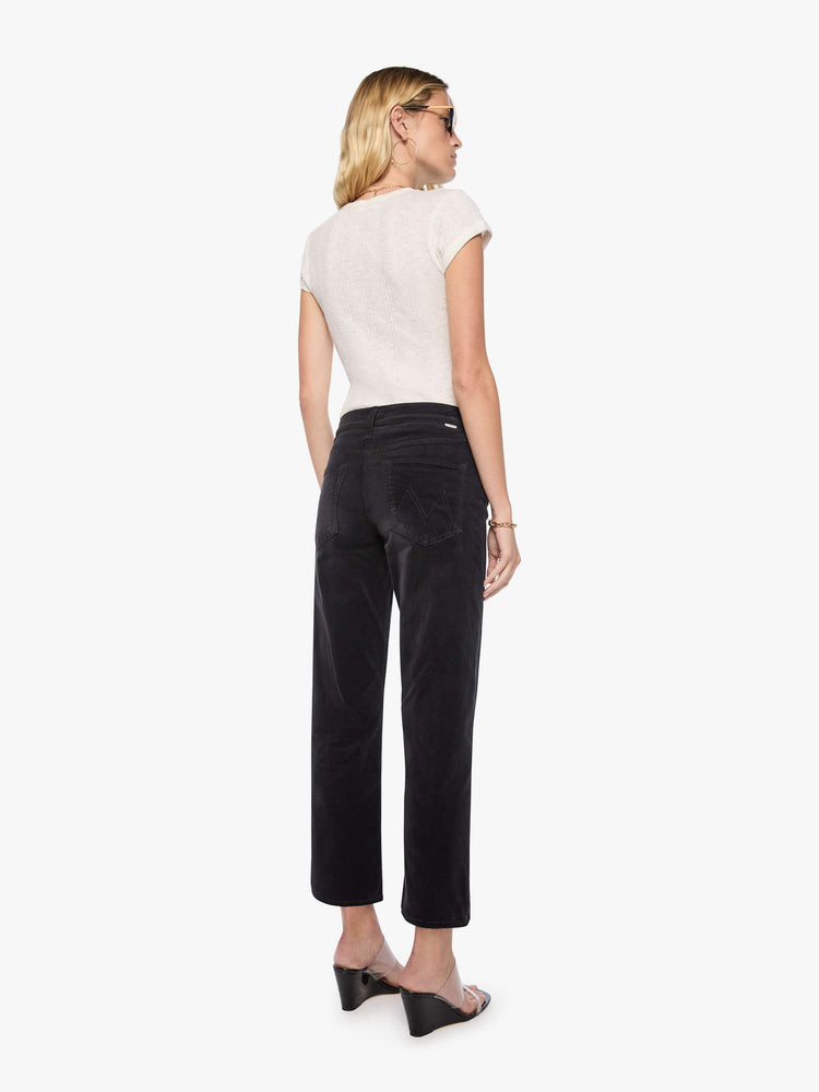 Back view of a woman in a black corduroy mid-rise straight-leg pants with a zip fly, ankle-length inseam and a clean hem.