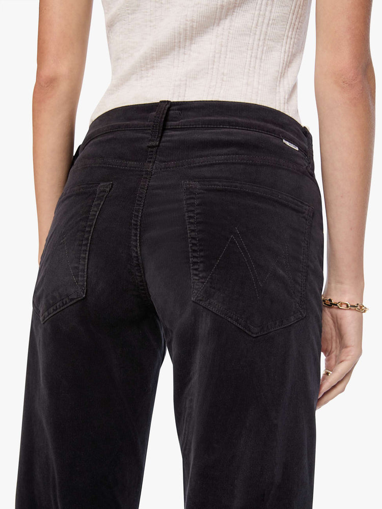 Close up view of a woman in a black corduroy mid-rise straight-leg pants with a zip fly, ankle-length inseam and a clean hem.