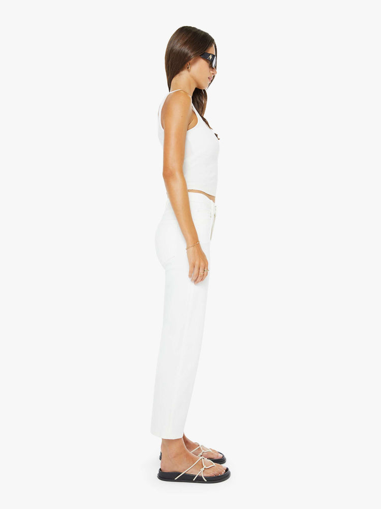 Side view of a woman in a white high-rise jeans with a straight leg, zip fly and an ankle-length inseam with a clean hem. 