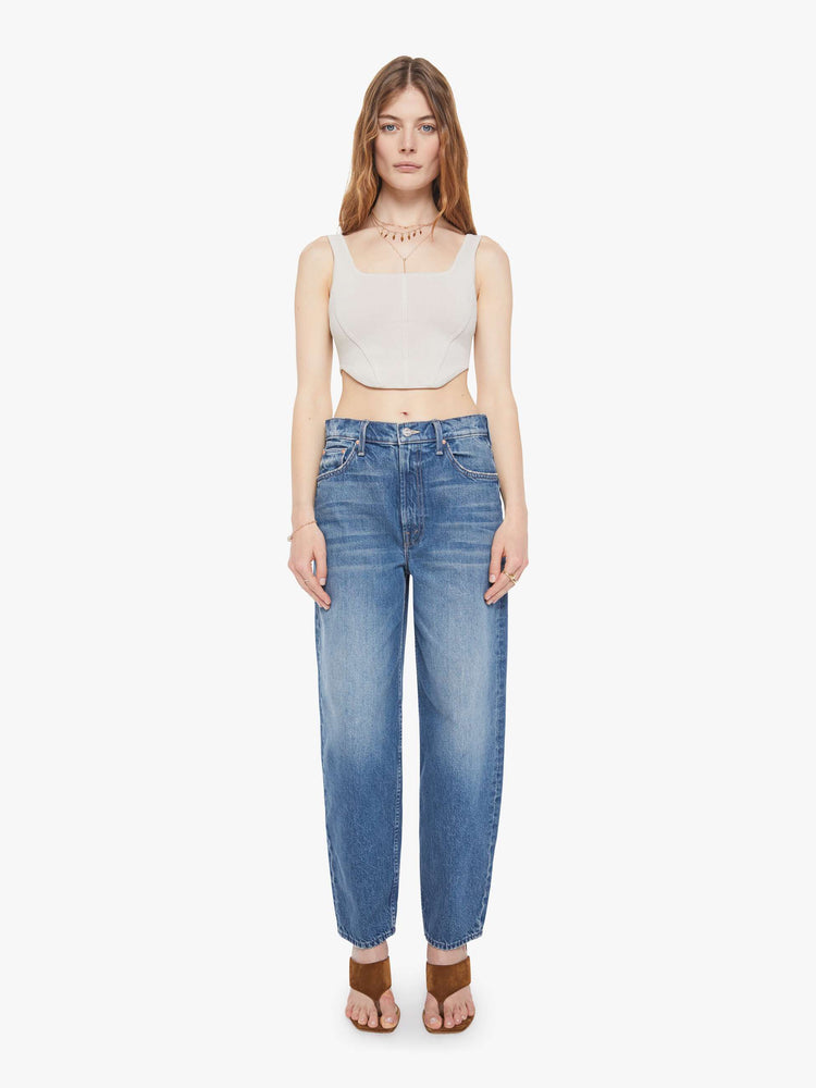 Front view of a woman in a super high-waisted barrel-leg jeans with a zip fly, ankle-length inseam and a clean hem.