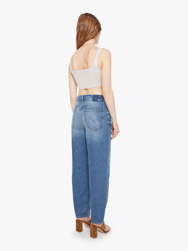 Back  view of a woman in a super high-waisted barrel-leg jeans with a zip fly, ankle-length inseam and a clean hem.