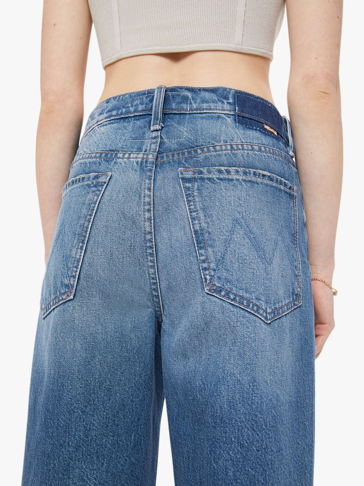 Back close up view of a woman in a super high-waisted barrel-leg jeans with a zip fly, ankle-length inseam and a clean hem.