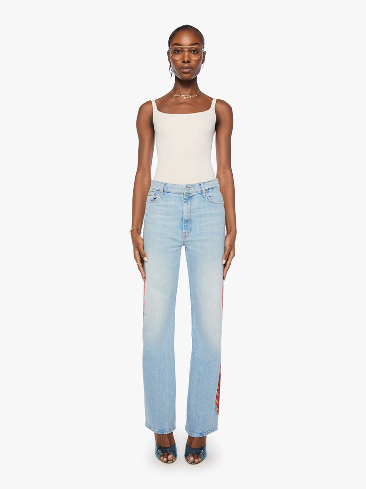 Front view of a woman n a light blue denim with flame on the side bootcut jeans with a high rise, zip fly and seamless finish on the outer leg.