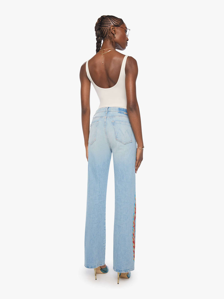 Back view of a woman n a light blue denim with flame on the side bootcut jeans with a high rise, zip fly and seamless finish on the outer leg.