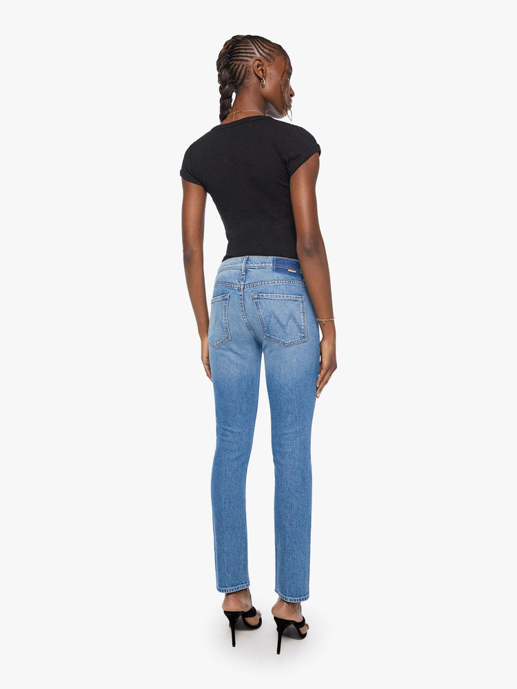 Back view of a woman in mid blue mid-rise jean has a straight leg, zip fly, 29-inch inseam and a clean hem. 