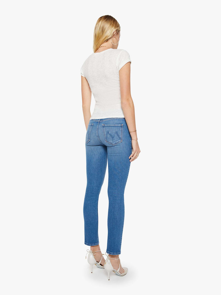 Back view of a woman in a mid blue mid-rise jean has a straight leg, zip fly, 29-inch inseam and a clean hem.