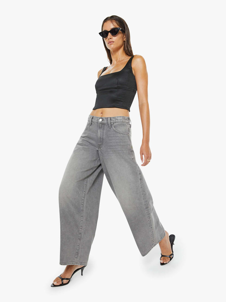 Walking view of a woman in a grey super high-waisted jeans have a low-slung fit, zip fly, loose wide-leg and a long 32-inch inseam with a clean hem.