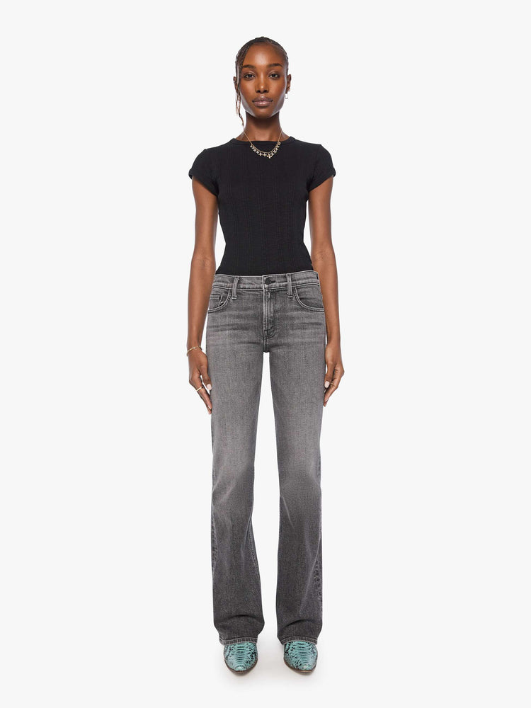 Front view of a woman in wash dark grey lower-rise bootcut jean with a long 32-inch inseam and a clean hem.