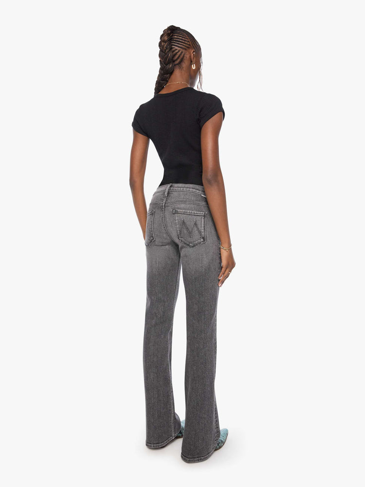 Back view of a woman in wash dark grey lower-rise bootcut jean with a long 32-inch inseam and a clean hem.