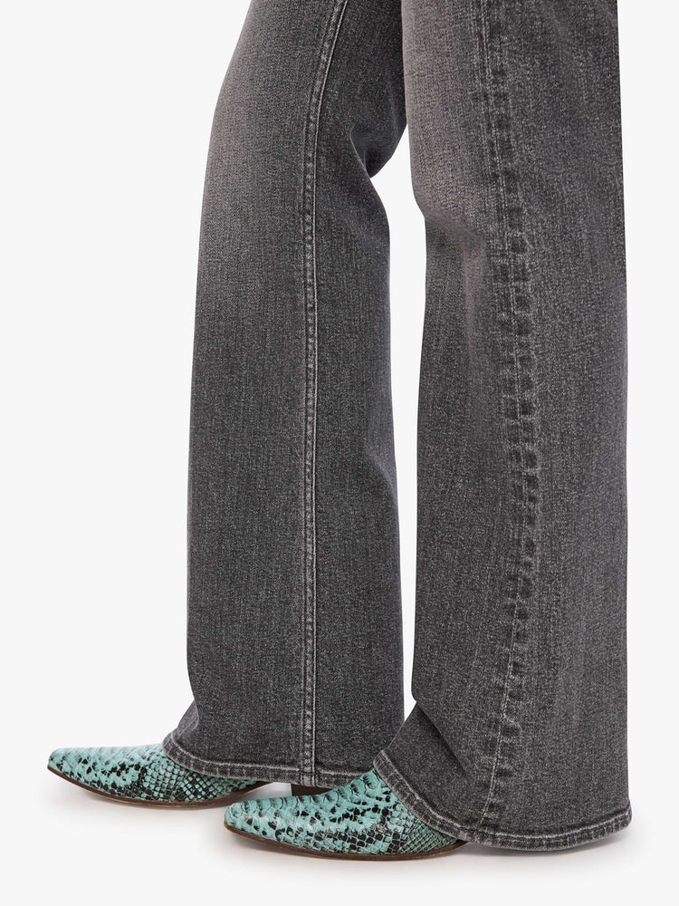Hem close up view of a woman in wash dark grey lower-rise bootcut jean with a long 32-inch inseam and a clean hem.