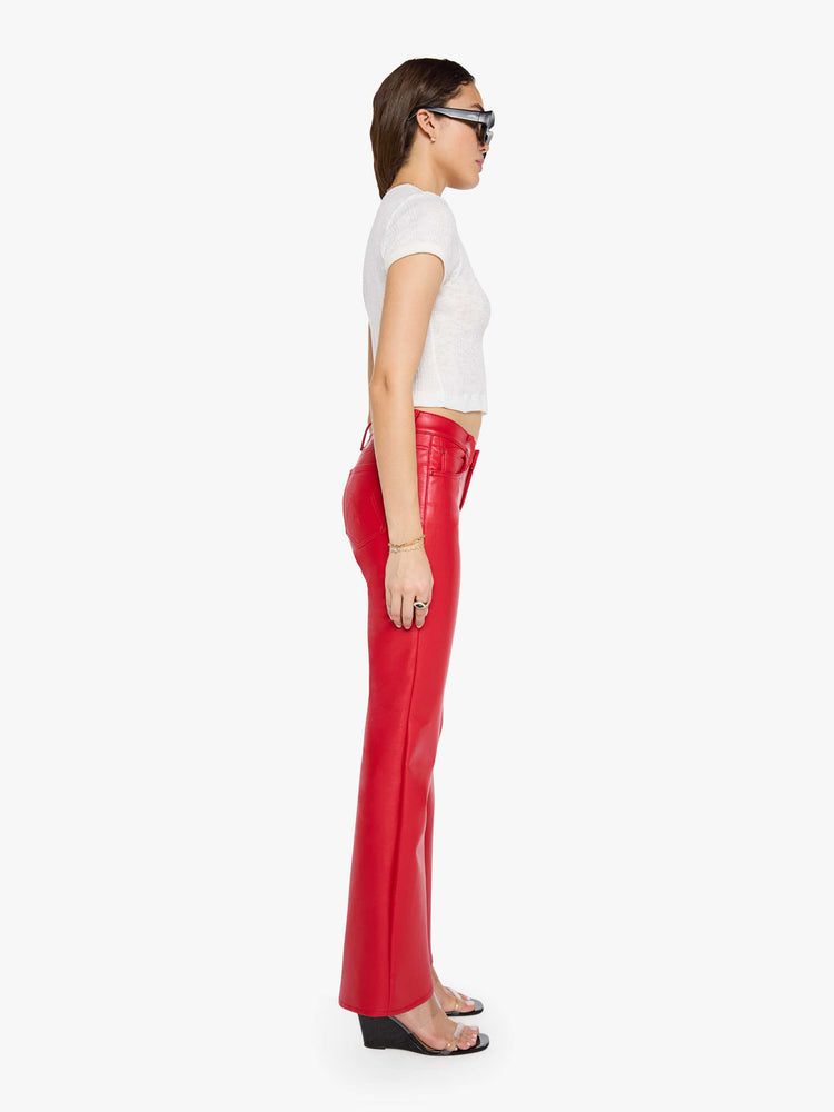 Side view of a woman in a cherry red lower-rise bootcut pant with a long 32-inch inseam and a clean hem.