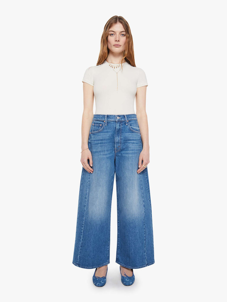 Front view of a woman in a mid-blue super high-waisted barrel-leg jeans with an ankle-length inseam, zip fly, clean hem and relaxed fit.