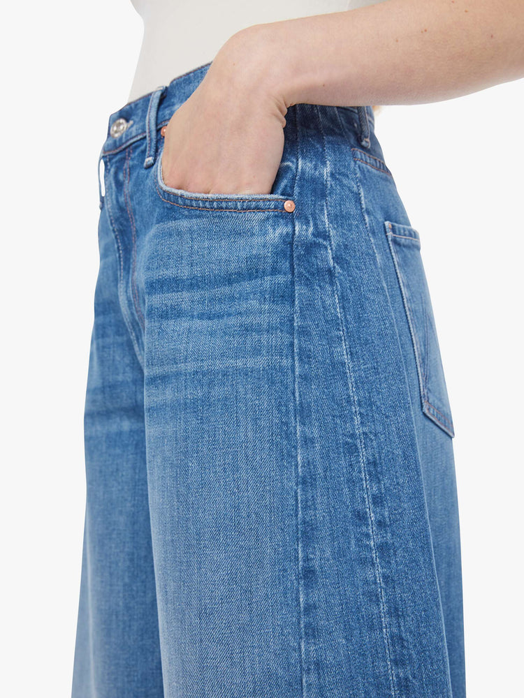 Close up view of a woman in a mid-blue super high-waisted barrel-leg jeans with an ankle-length inseam, zip fly, clean hem and relaxed fit.