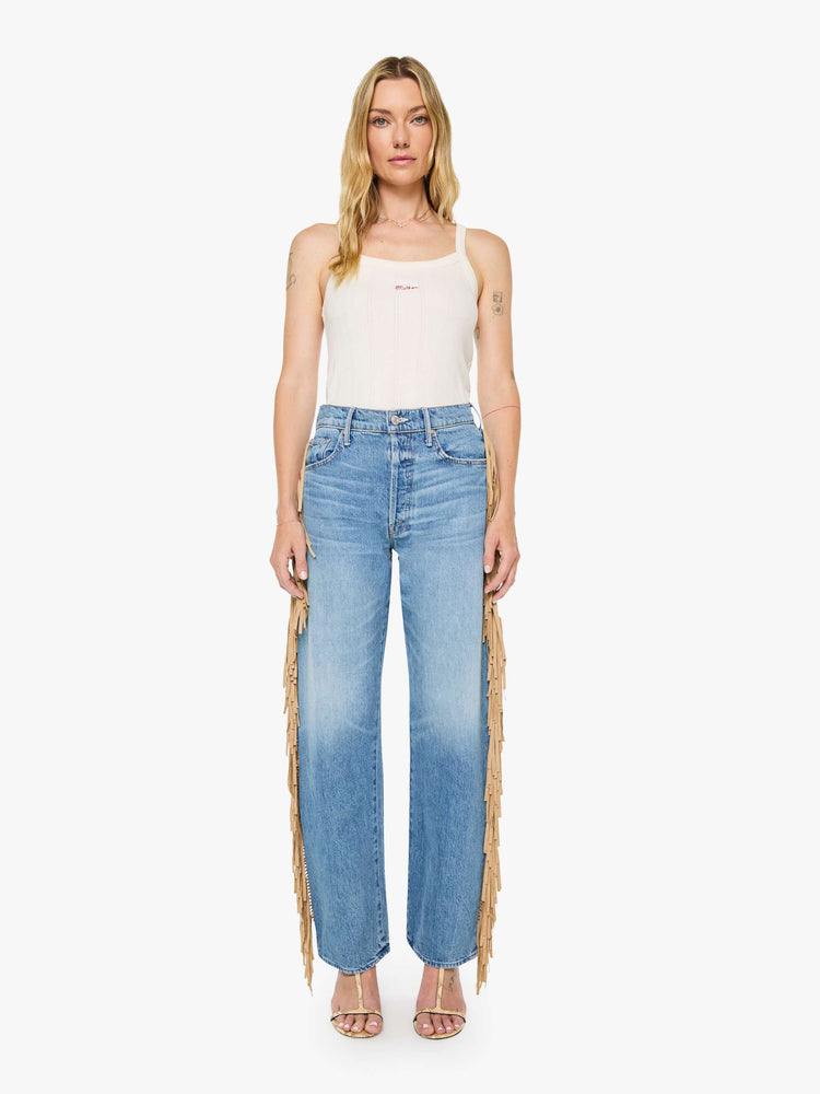 Front view of a woman in a mid blue with whiskering, fading at the knees and faux-suede fringe down the outer seam super high-waisted jean with a wide, curved leg, button fly, long 32-inch inseam and a clean hem. 