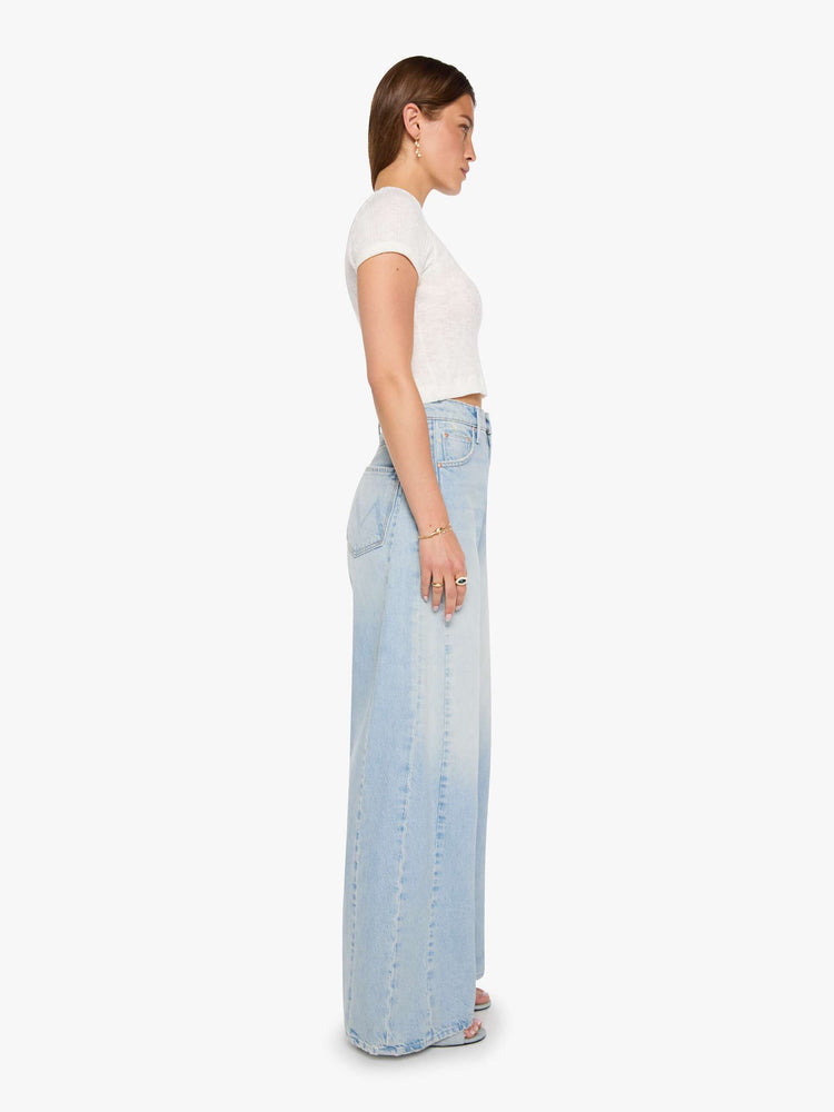 Side view of a woman in a light blue super high-waisted barrel-leg jeans with a relaxed fit, zip fly, inset panels on the outer seams, long 32-inch inseam and a clean hem.
