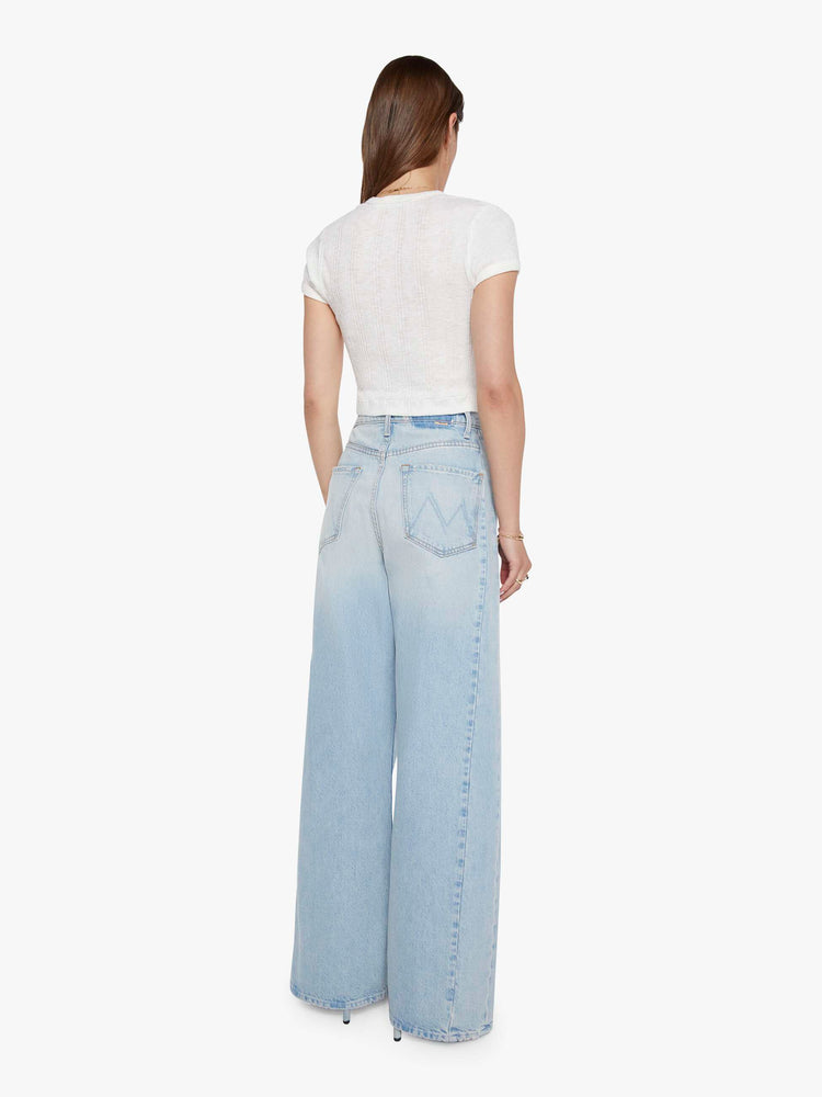 Back view of a woman in a light blue super high-waisted barrel-leg jeans with a relaxed fit, zip fly, inset panels on the outer seams, long 32-inch inseam and a clean hem.