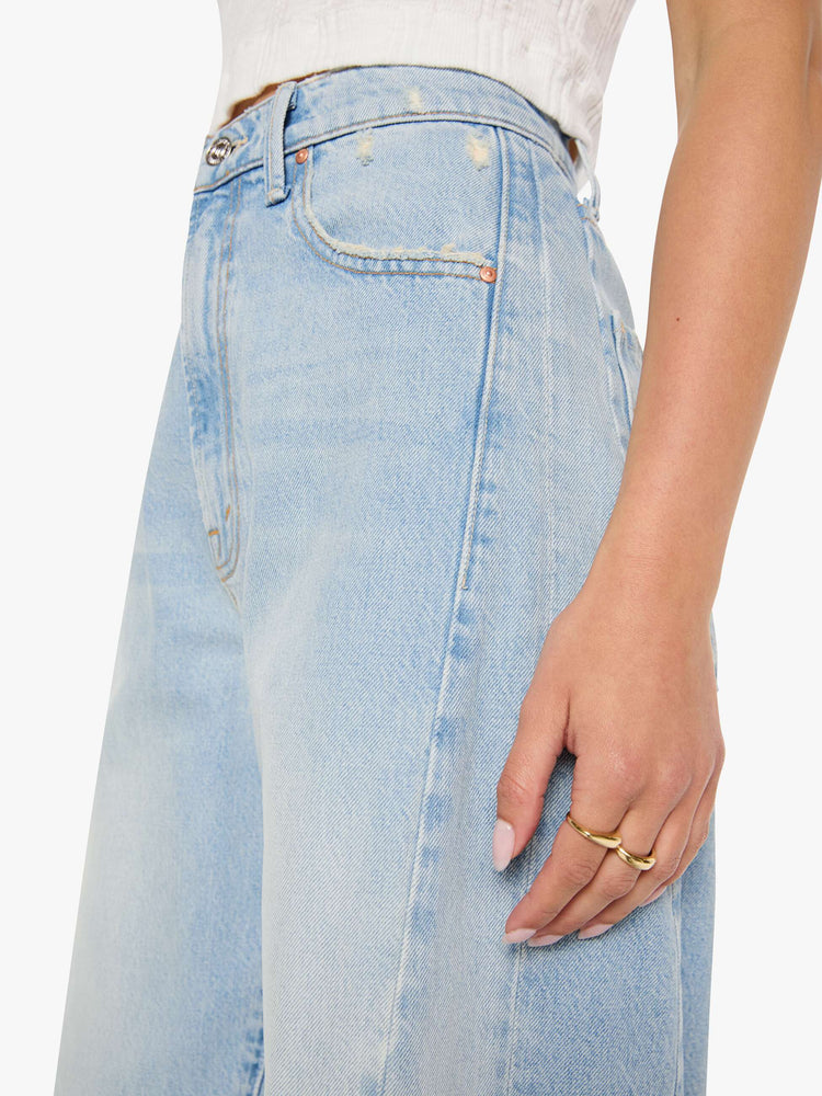 Close up view of a woman in a light blue super high-waisted barrel-leg jeans with a relaxed fit, zip fly, inset panels on the outer seams, long 32-inch inseam and a clean hem.