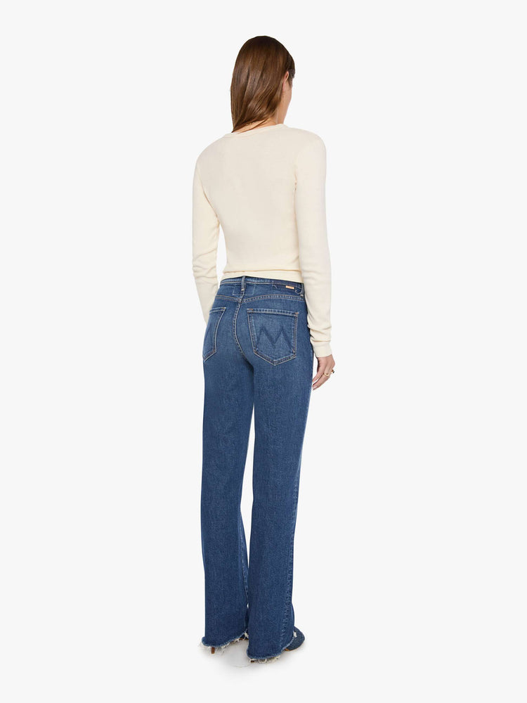 Back view of a woman in a med blue high-rise straight-leg jean with a zip fly, 31-inch inseam and a frayed hem.
