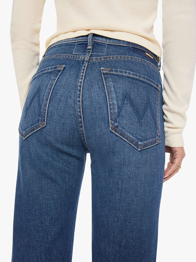 Close up view of a woman in a med blue high-rise straight-leg jean with a zip fly, 31-inch inseam and a frayed hem.