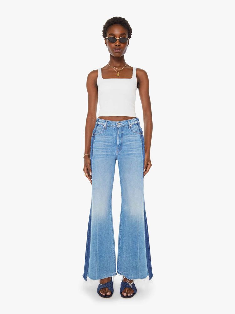 Front view of a woman in a high-waisted wide-leg jeans with a long 32-inch inseam and a frayed, uneven hem in a mid blue wash with darker panels down the outer leg.