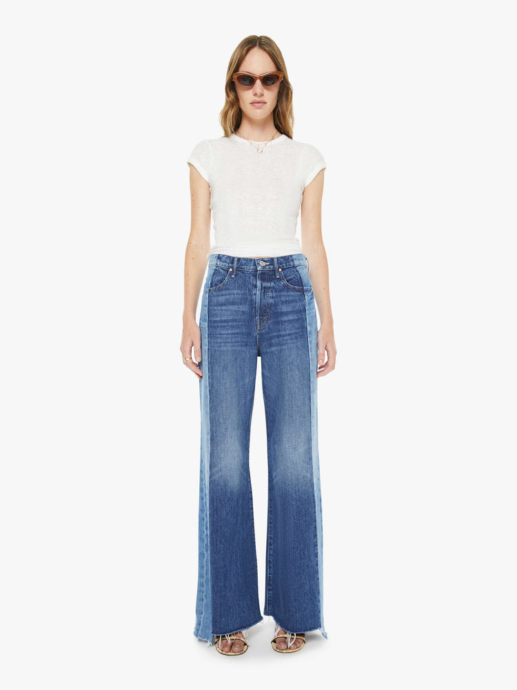 Front view of a woman in mid blue high-waisted wide-leg jeans with a button fly, long 32-inch inseam and a frayed, uneven hem.