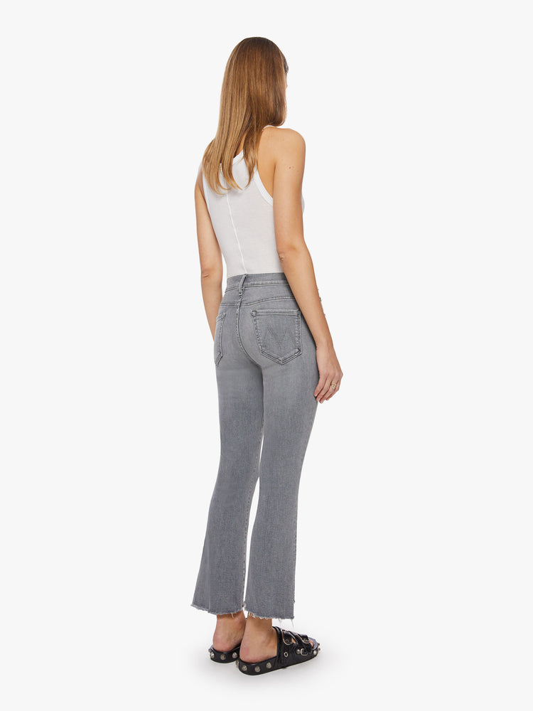 Back view of a woman grey hue high-waisted bootcut hits at the ankle with a frayed step-hem.