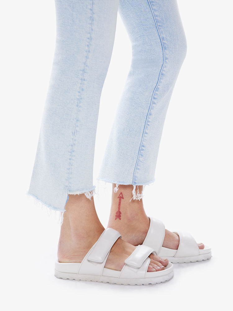 Hem close up view of womens high-waisted bootcut hits at the ankle with a frayed step-hem in a light blue hue.