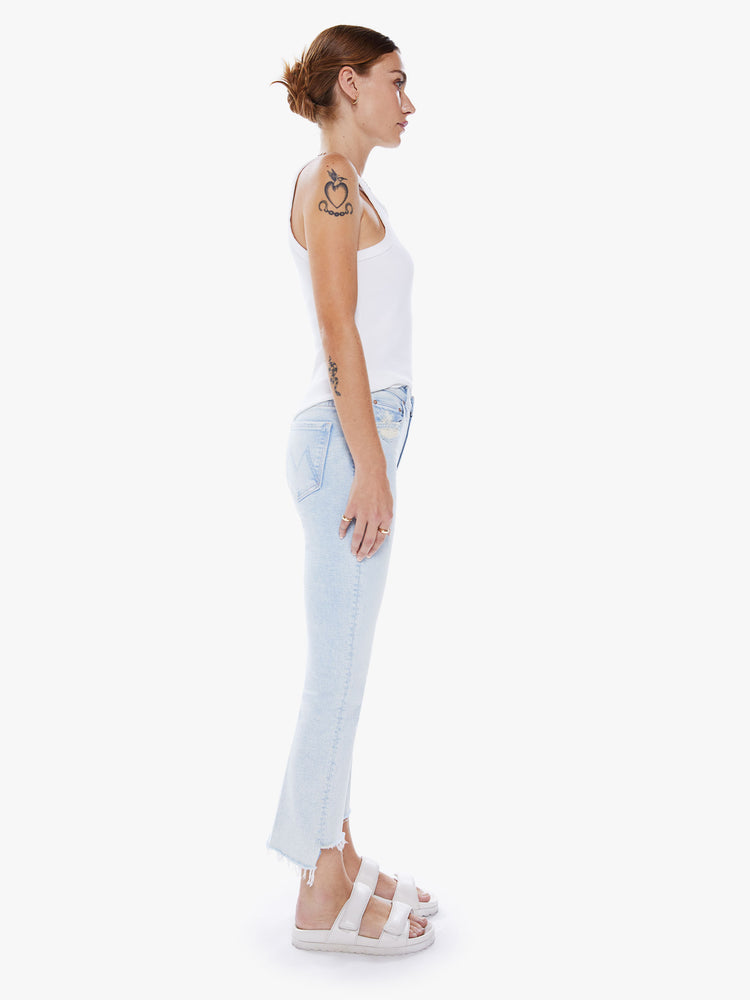 Side view of womens high-waisted bootcut hits at the ankle with a frayed step-hem in a light blue hue.