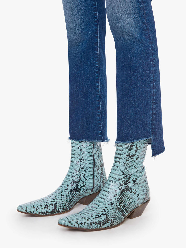 Close up hem view of a woman in a high-waisted bootcut has a zip fly, ankle-length inseam and a frayed step-hem.