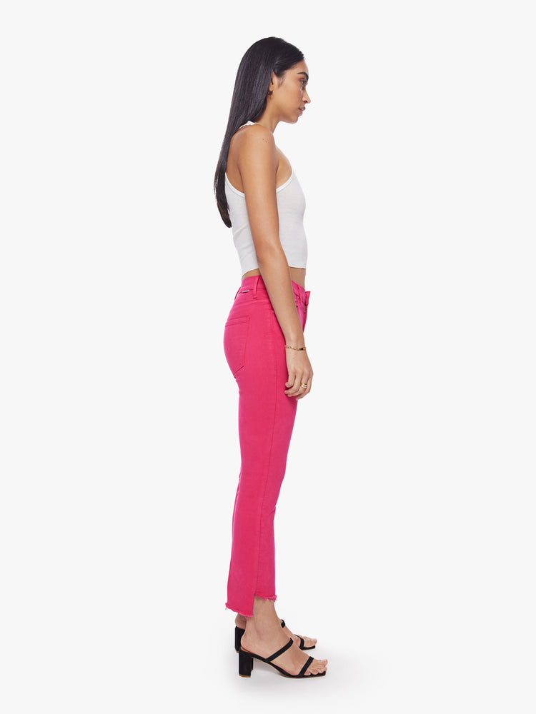 Side view of a woman high-waisted bootcut hits at the ankle with a frayed step-hem in a hot pink hue.