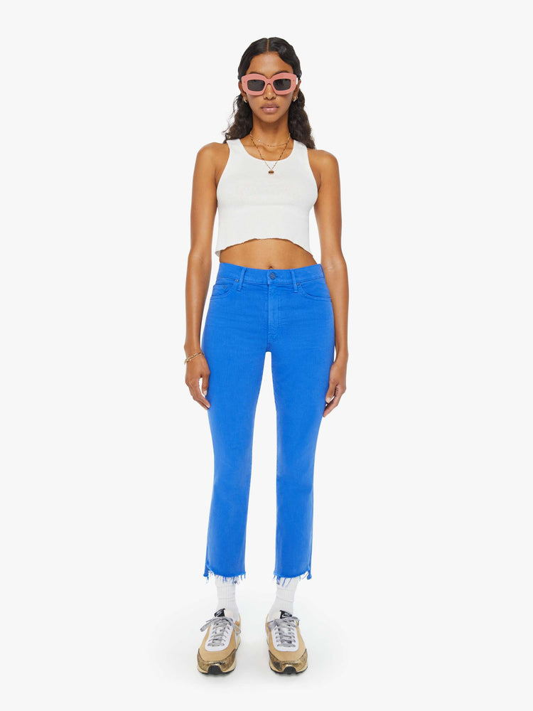 Front view of a woman in bright blue high-waisted bootcut that is cropped above the ankle with a frayed step-hem.
