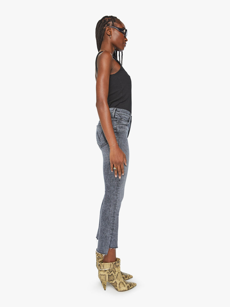 Side view women's high waisted mineral wash black straight leg denim with step fray hem detail.