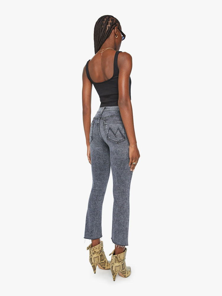 Back view women's high waisted mineral wash black straight leg denim with step fray hem detail.