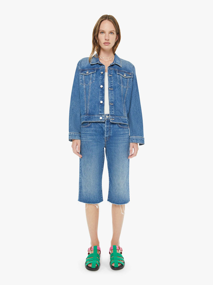 Front view of a woman in a classic blue high-rise straight leg denim capri with a zip fly, 16-inch inseam and a frayed hem.