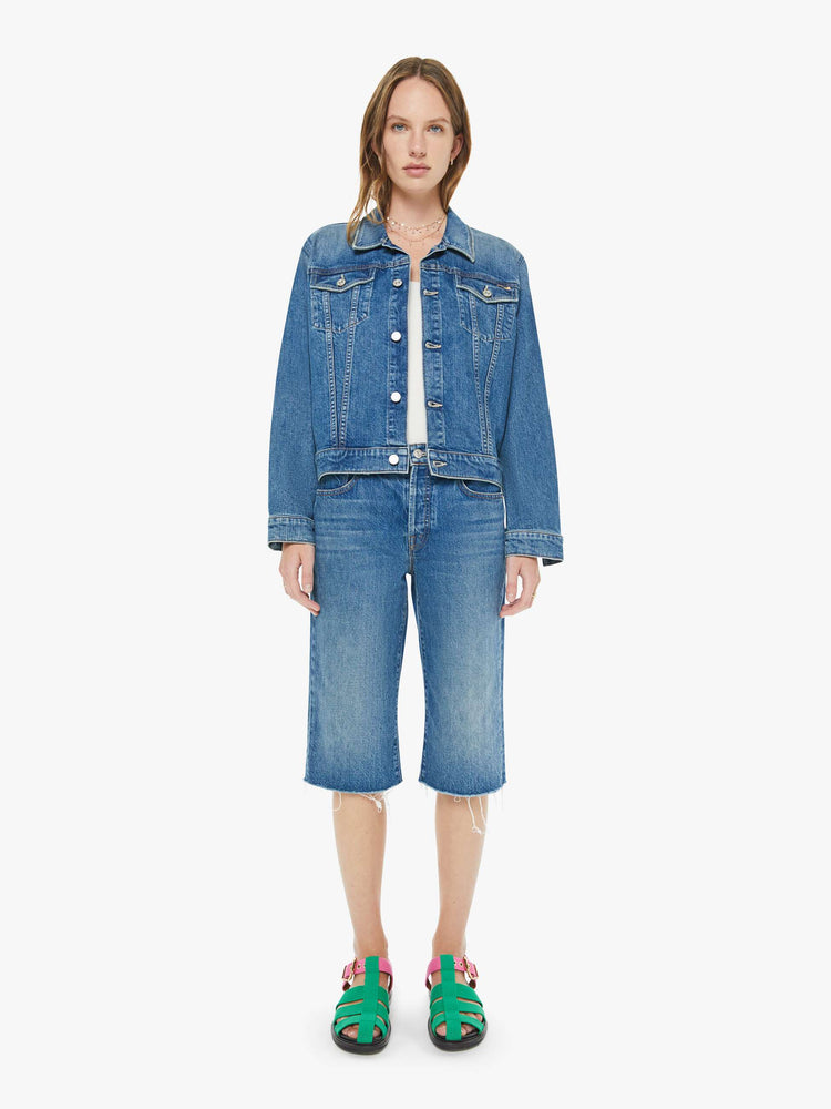 Front view of a woman in a classic blue high-rise straight leg denim capri with a zip fly, 16-inch inseam and a frayed hem.