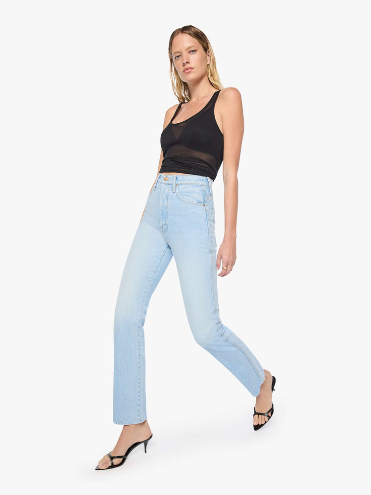 Walking view of a woman in a light blue  super high-waisted pants have a button fly, slightly tapered straight leg, a long 32-inch inseam and a clean hem. 