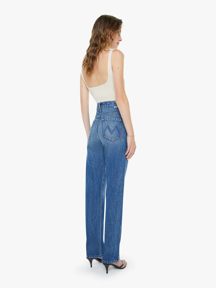 Back view of a woman in a mid blue super high-waisted pants have a button fly, slightly tapered straight leg, a long 32-inch inseam and a clean hem.
