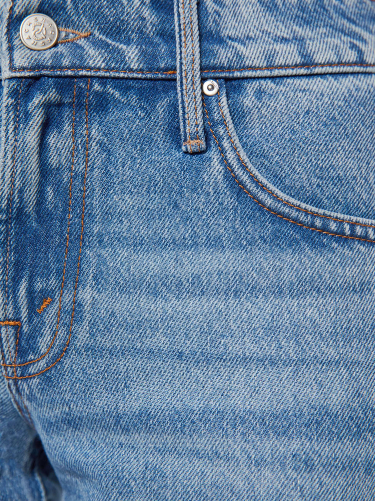 Swatch view of a woman in lower-rise jeans have a straight leg, zip fly and an ankle-length inseam with light blue fringe along the hem.
