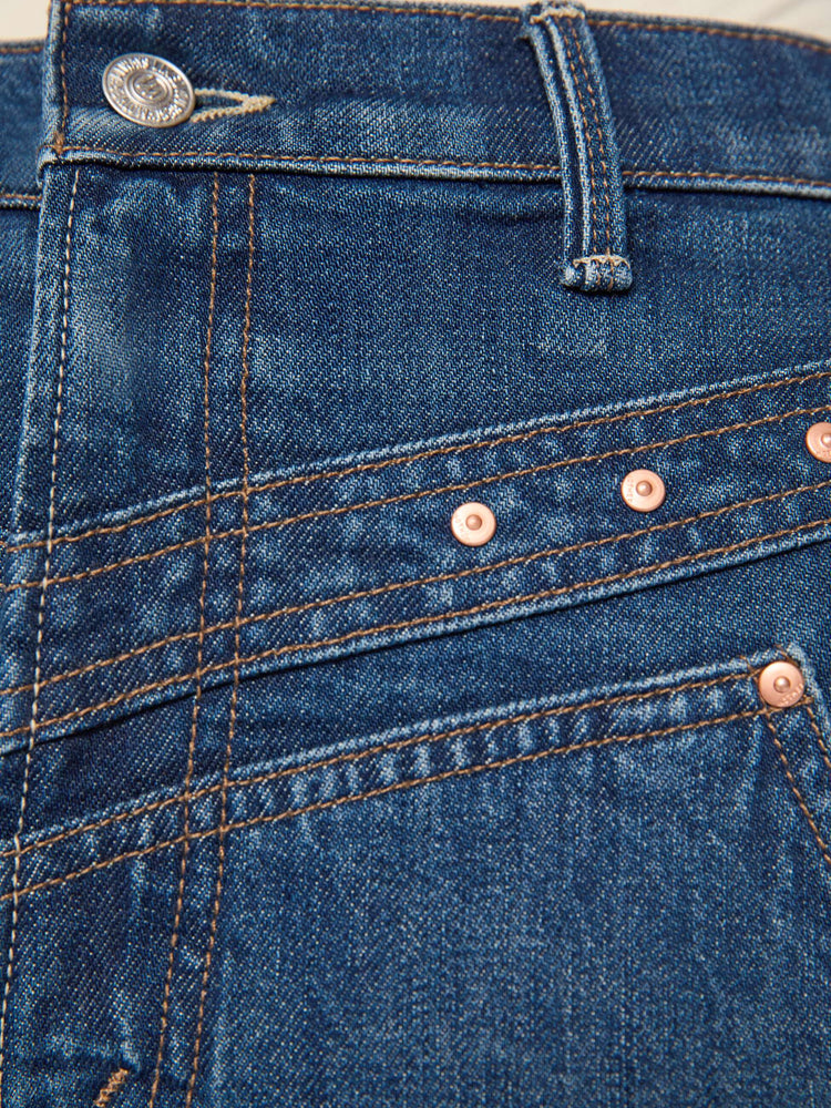 Swatch view of a woman in mid-blue with fading at the knees and rivet details on the front high-rise straight-leg jean with angled, Western-inspired seams at the waist, a zip fly, 29-inch inseam and a clean hem.