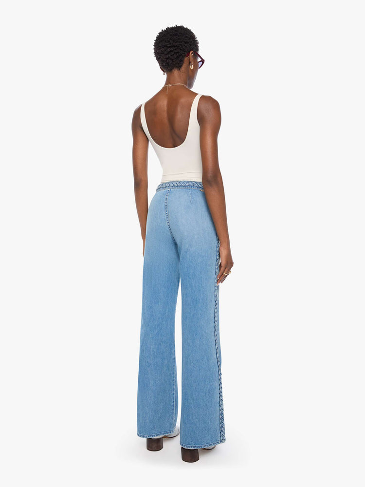 Back view of a woman in light blue with braided details along the waist and down the outer seam, wide leg jeans with a high rise, zip fly, 32-inch inseam and a clean hem. 