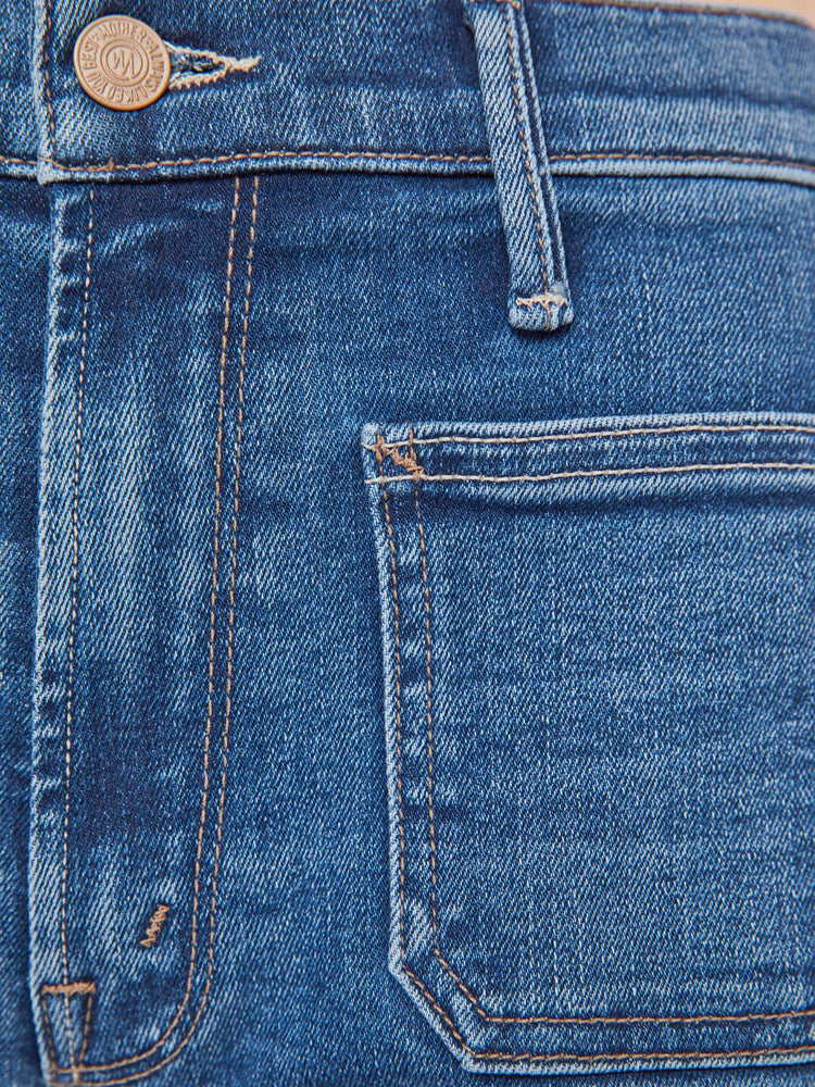 Swatch view of a woman in a med blue mid-rise jeans with a loose fit, zip fly, wide leg, patch pockets and ankle-length inseam with a clean hem.